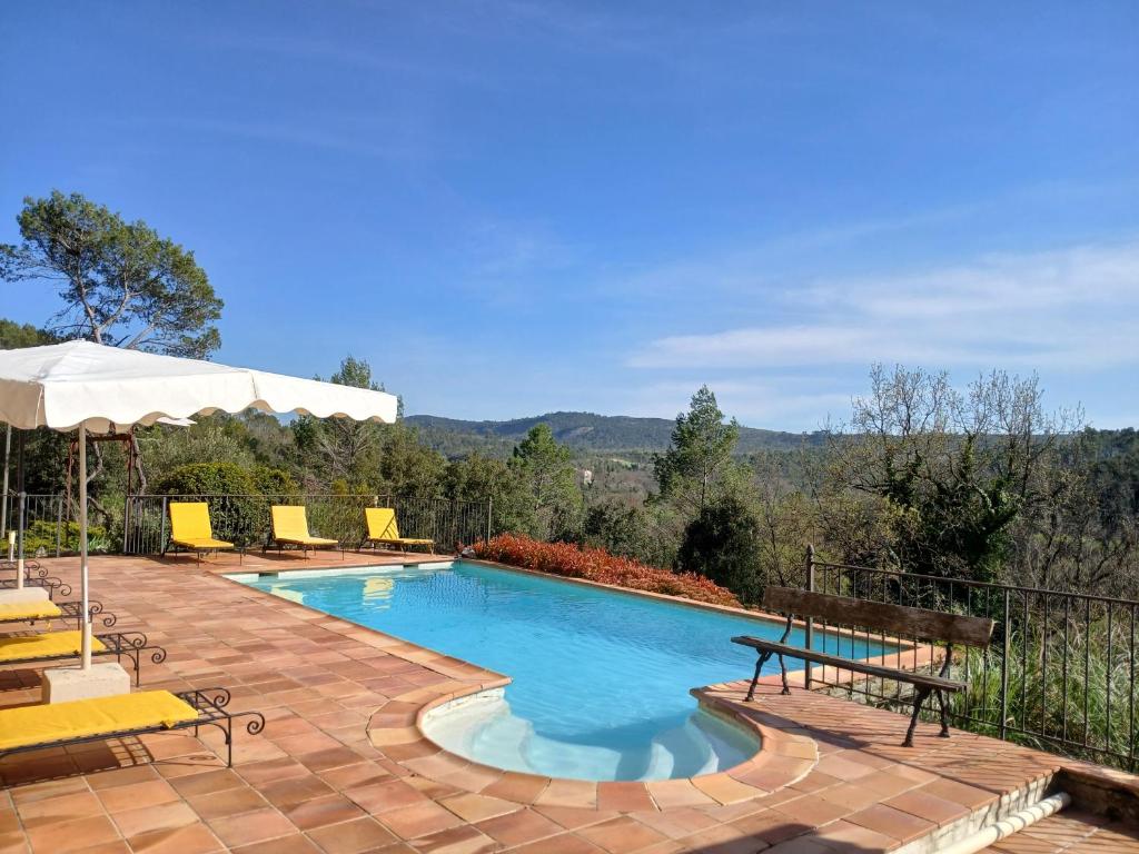 une piscine avec des chaises et un parasol dans l'établissement Le Pijouret - Appt avec piscine privée, à Brignoles