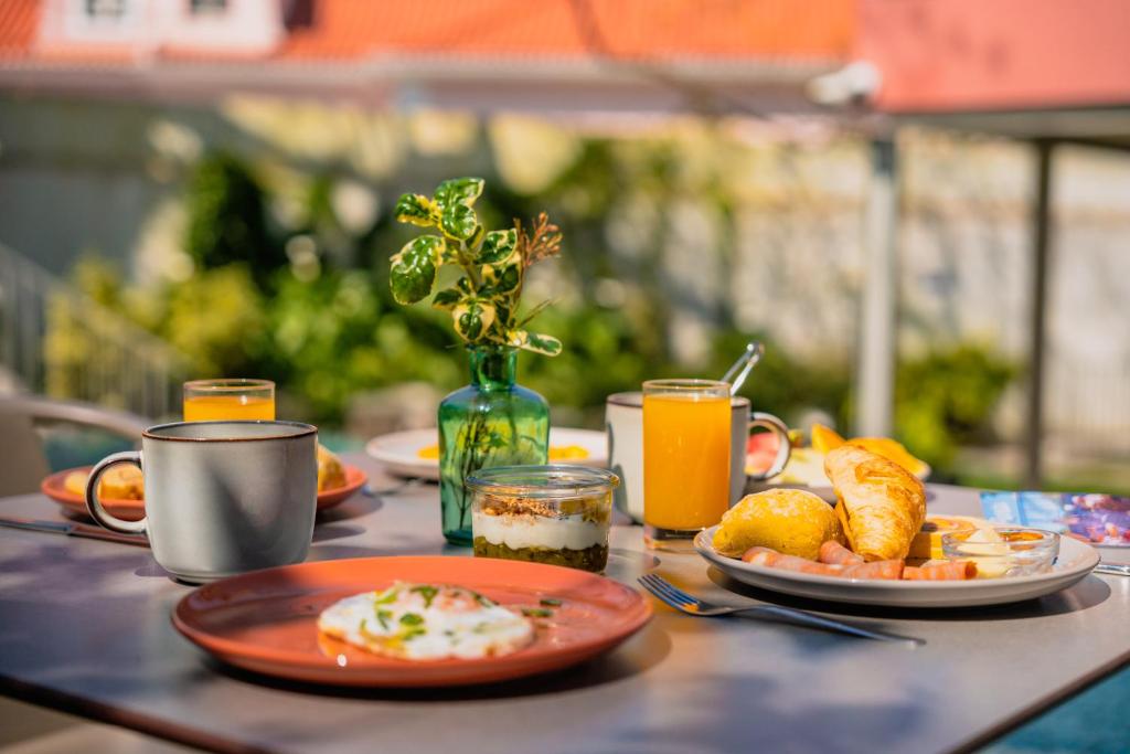 An outdoor breakfast table set with pastries, fruit, drinks and prepared food.