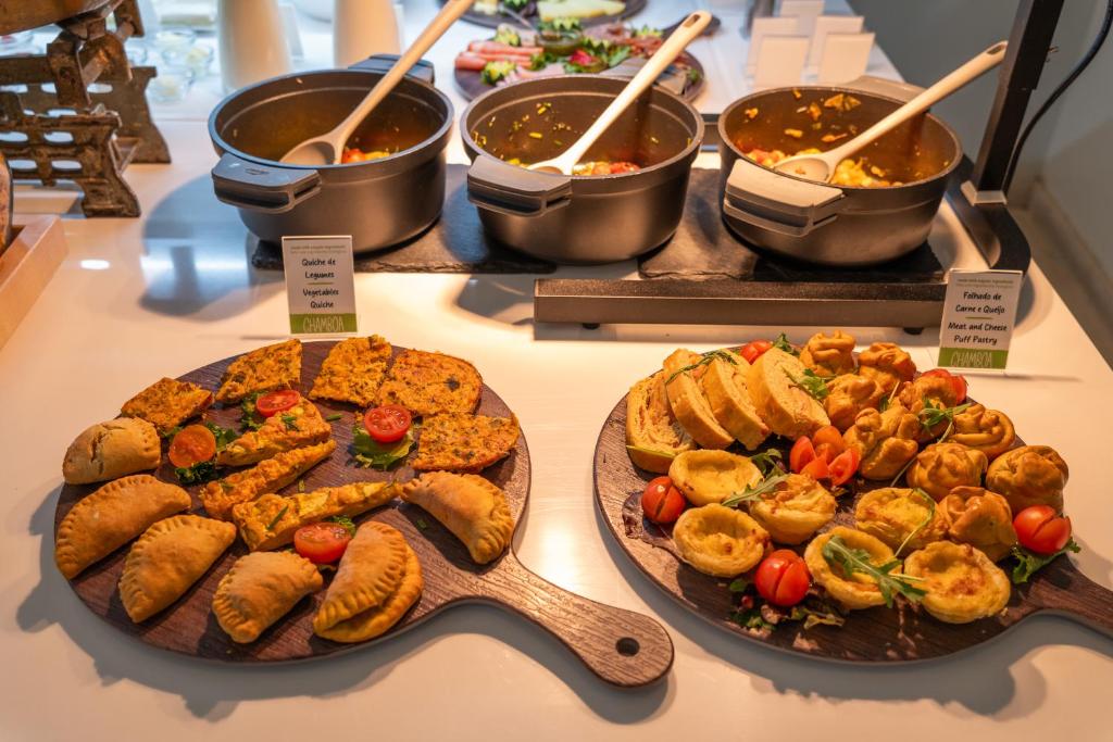 A close-up of prepared savoury breakfast dishes, pastries and labelled hot pots.