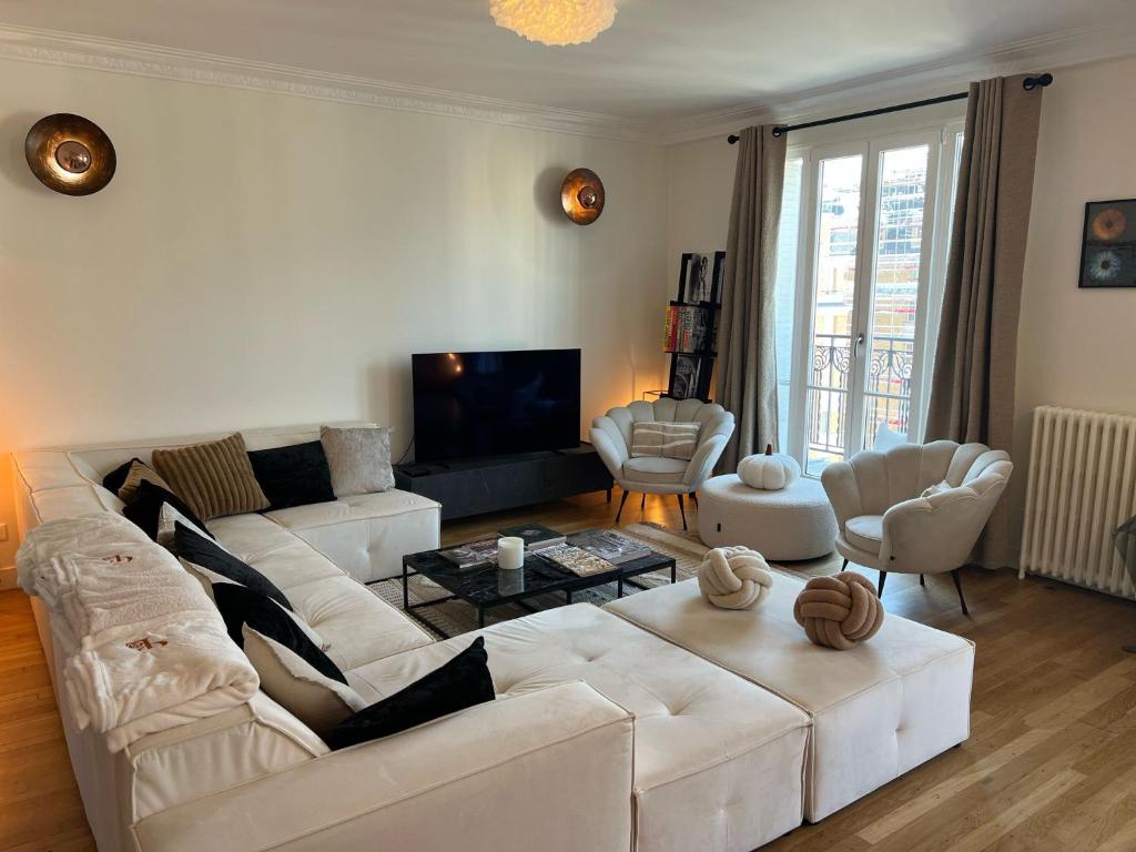 un salon avec un canapé blanc et une télévision dans l'établissement L'élégance à la Parisienne, à Paris