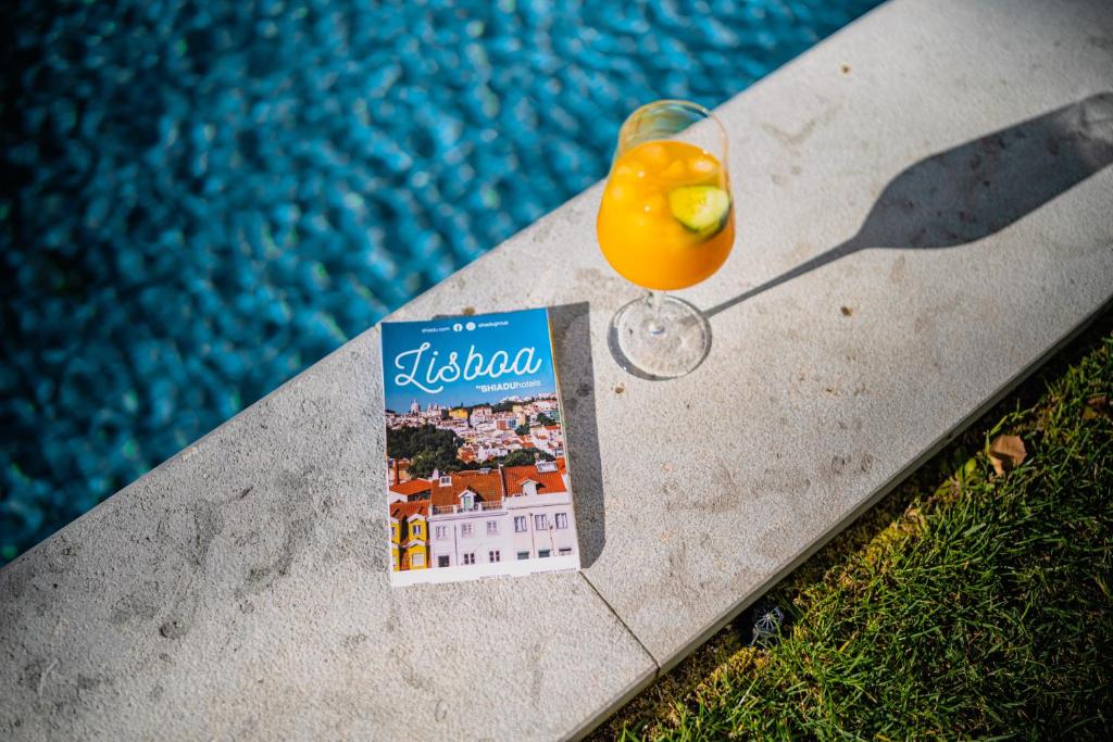 A poolside detail with a Lisbon guidebook and orange drink on the pool coping.