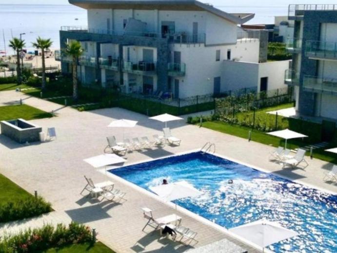 a large swimming pool with chairs and a building at Macrinum - LE DUNE in Silvi Marina
