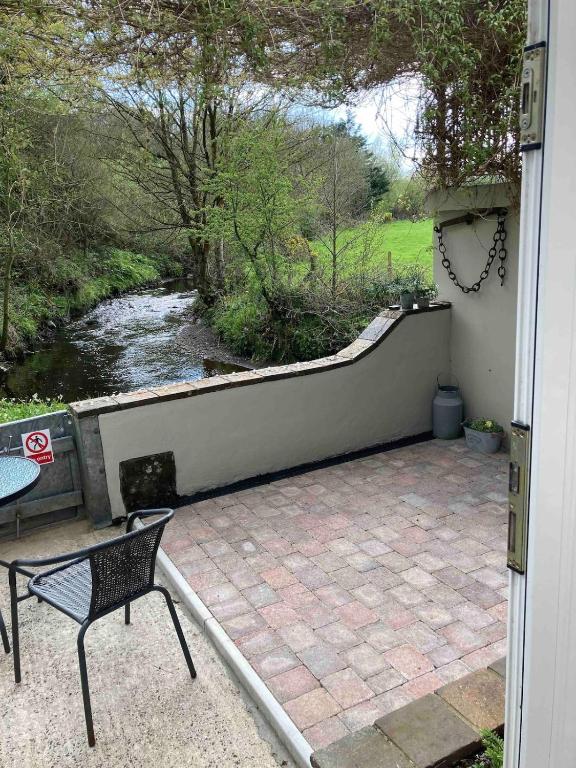 a patio with a table and a chair next to a river at Mill River Retreat in Castlerock