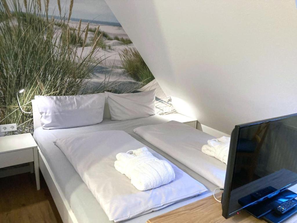 un letto bianco con asciugamani accanto a una scrivania di Inselresidenz Strandburg Juist FeW a Juist