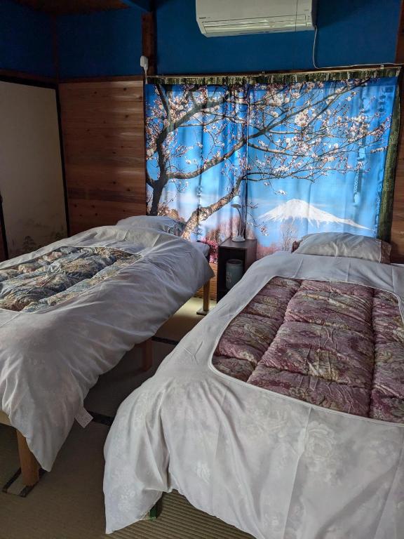 a room with three beds and a blue wall at Guest house AIZU First in Aizuwakamatsu