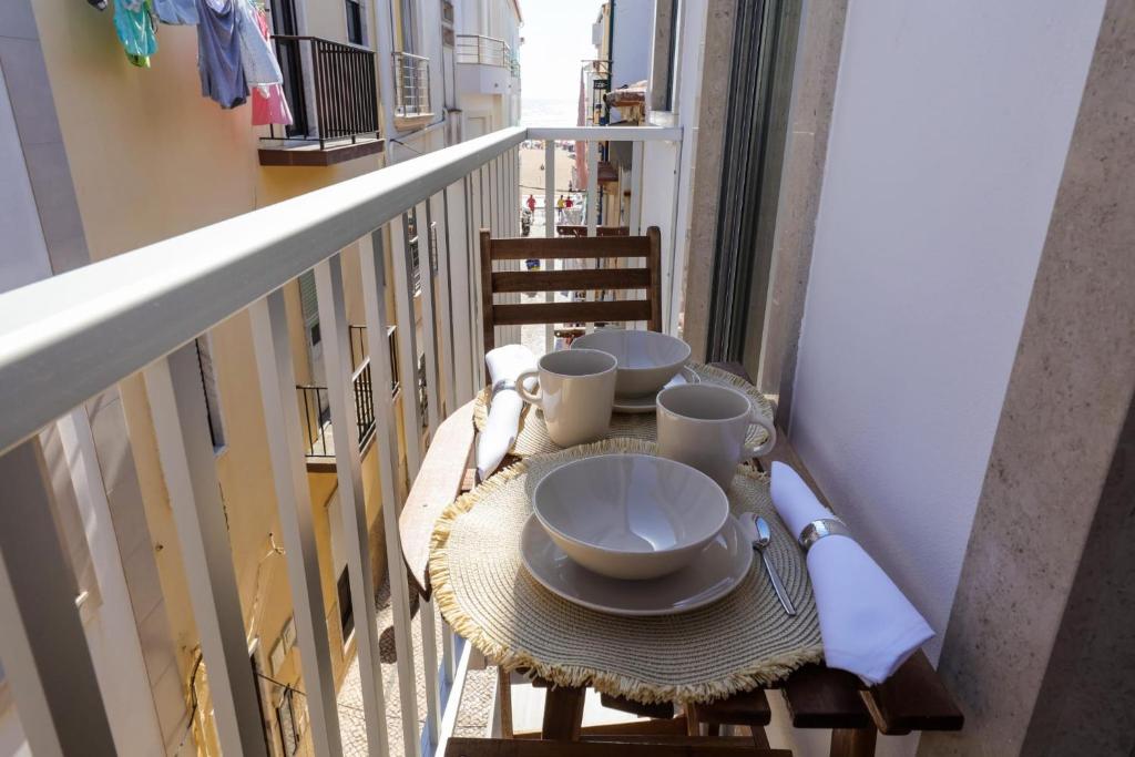 a table with plates and cups on a balcony at Casinha da Rosa in Nazaré