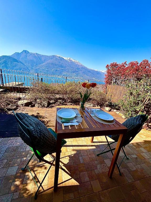 a wooden table with two chairs and a vase of flowers at residenza gelsomino - relax and view in Bellano