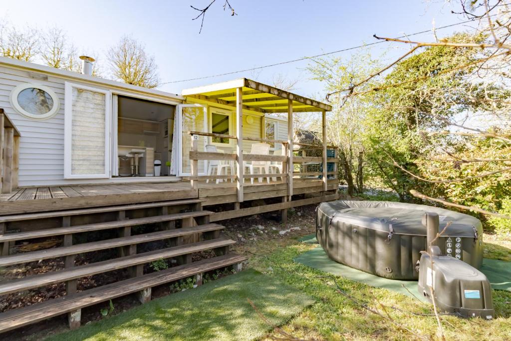 a house with a bath tub sitting on a deck at Mobilhome O’Hara 884 in Bouzic