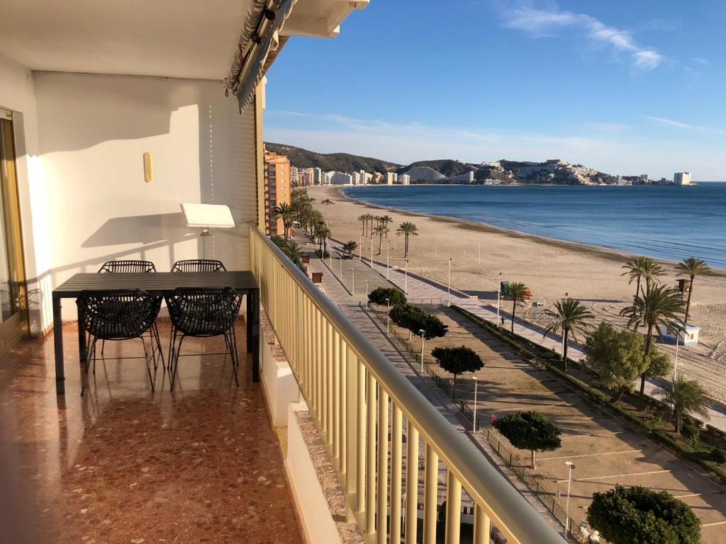 einen Balkon mit Tisch und Stühlen und einen Strand in der Unterkunft Cullera-Apartment in Cullera