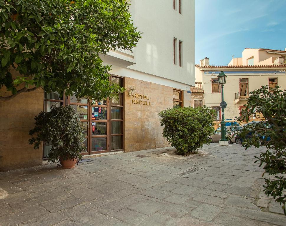 un edificio con una calle con árboles delante de él en Nefeli Hotel en Atenas