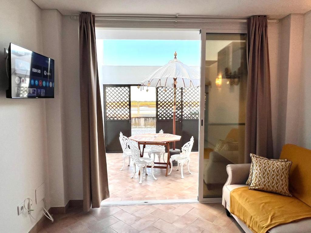 a living room with a couch and a table and chairs at Refúgio da Ria By ALGARTUR in Cabanas de Tavira