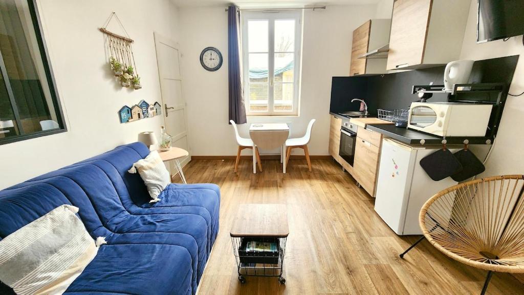 un salon avec un canapé bleu et une cuisine dans l'établissement Les pieds dans l'eau, à Veules-les-Roses
