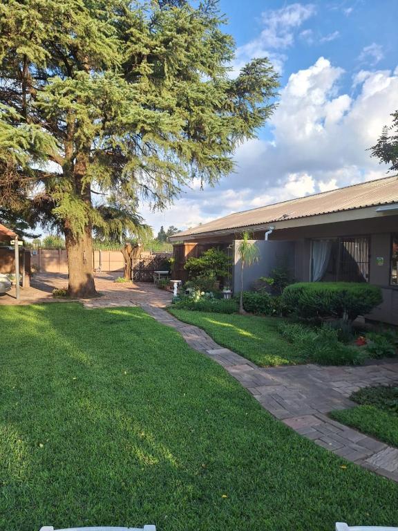 a house with a tree next to a yard at Country Route LTX in Lichtenburg