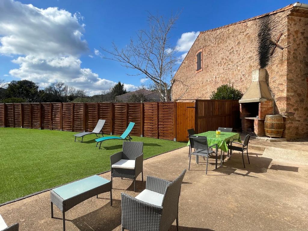 d'une terrasse avec des chaises, une table et une pelouse. dans l'établissement Évasion ensoleillée avec jacuzzi à Cazedarnes, à Cazedarnes