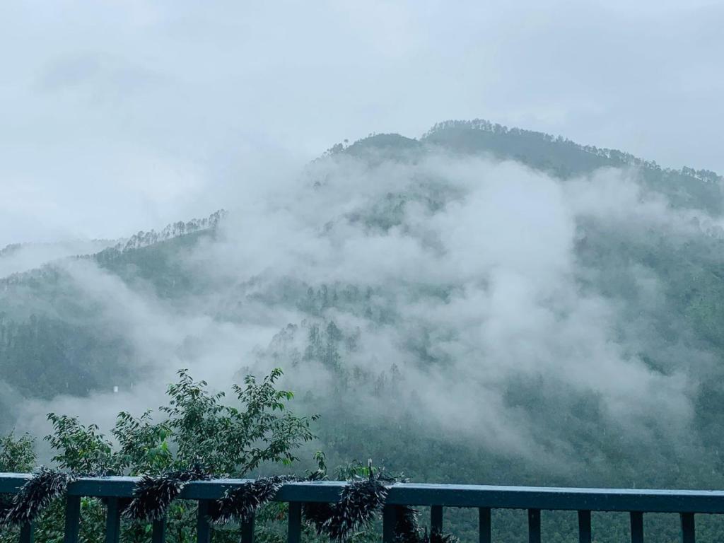 a mountain obscured by clouds with a fence in the foreground at Tatsaaraa Kavan in Rāmgarh