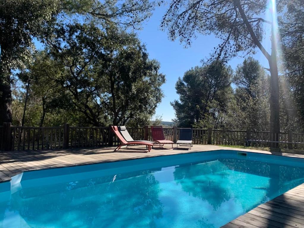 una piscina con 2 sillas de jardín junto a ella en Villa Natura, en Saint-Jean-de-Cuculles