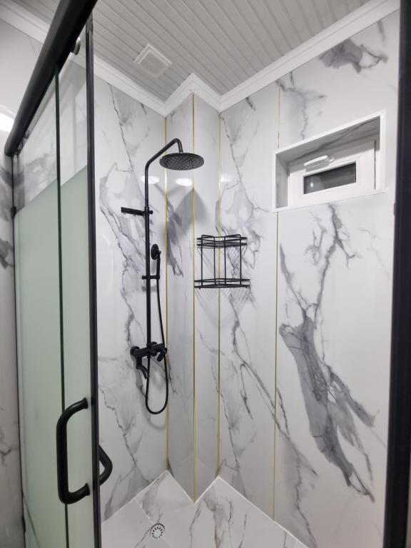 a bathroom with a shower with marble walls at Turkistan apart Hotel ближе Караван сарая in Türkistan