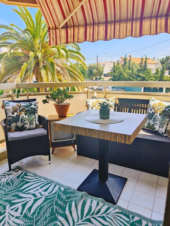 une table et des chaises sur un balcon avec un parasol dans l'établissement Bel appartement à 50m de la plage, 2 pièces climatisées, parking privé, à Antibes