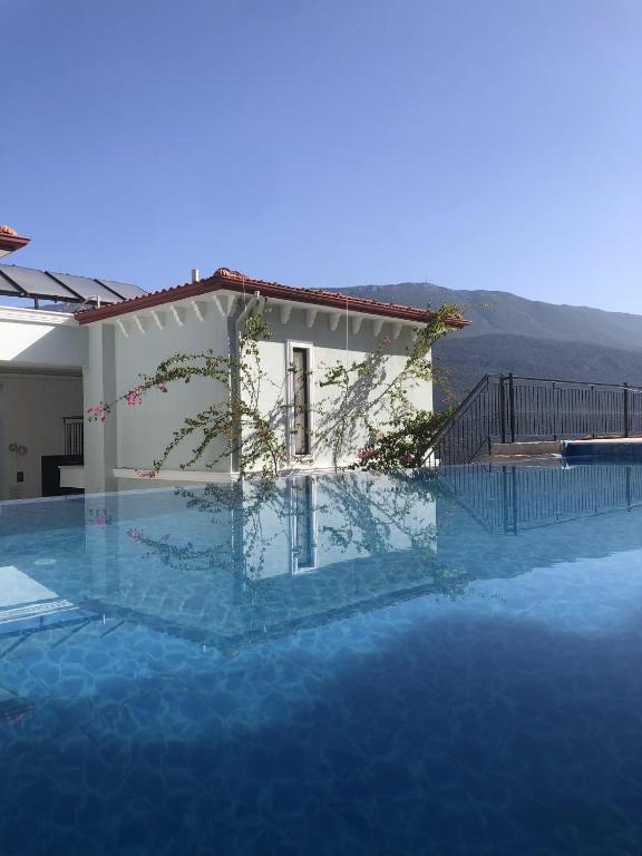 a large swimming pool with a house in the background at Gümüş Yazar Hotel in Kaş