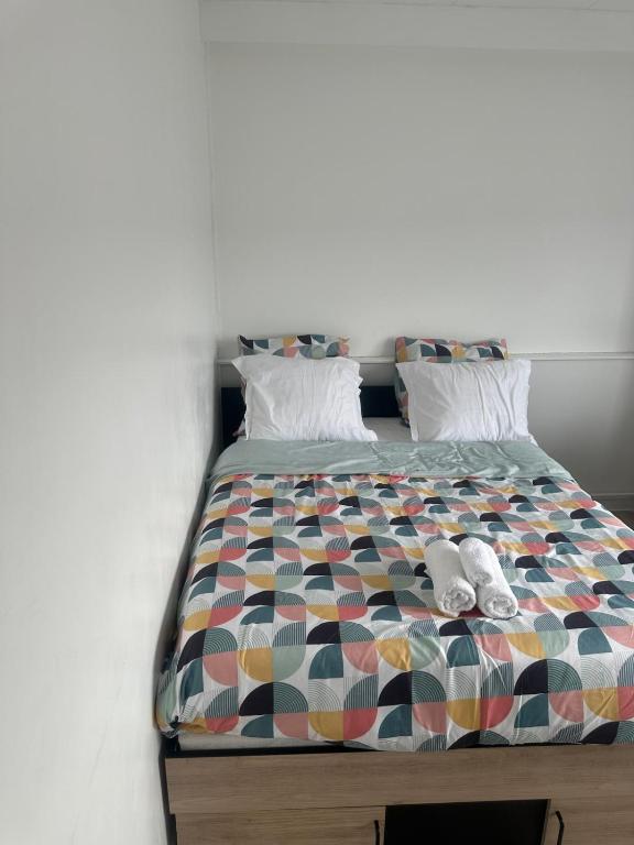 - un lit avec une couette colorée et 2 chaussures dans l'établissement Appart de 5 chambres sur Nancy, à Nancy