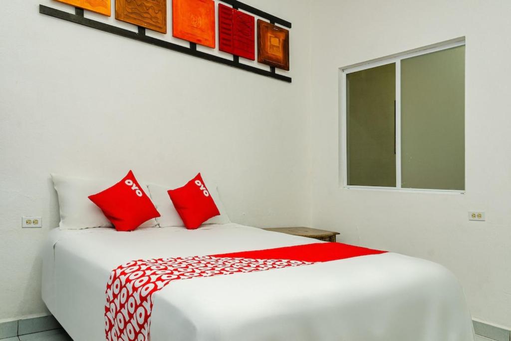 a white room with a bed with red pillows at OYO Hotel Cabo Del Sur, Cabo San Lucas in Cabo San Lucas