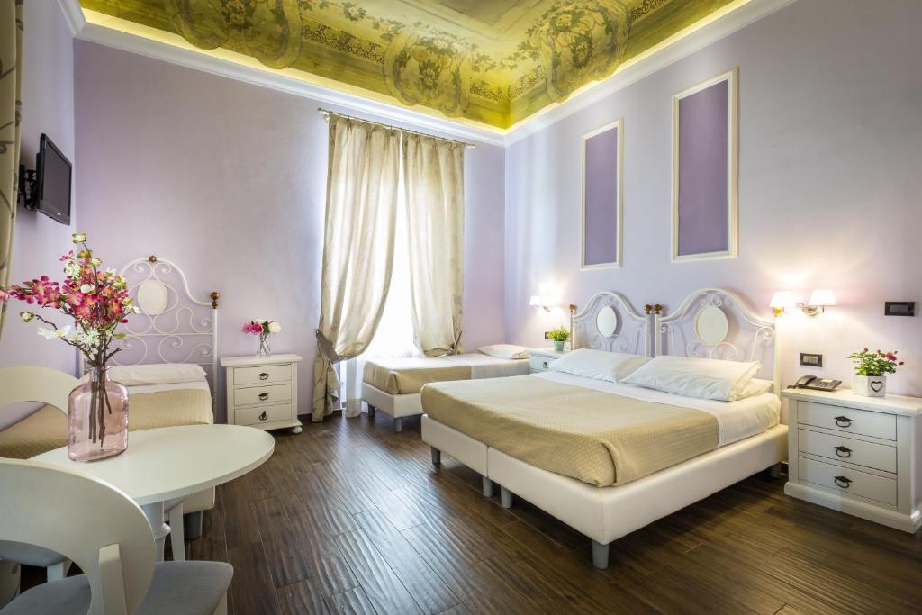 a bedroom with two beds and a table with flowers on it at Hotel Ferrucci in Florence