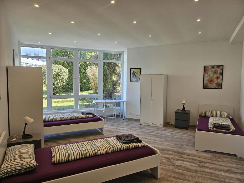 BaienfurtにあるBaienfurt - large house with 3 apartments with 3-4 bedrooms near Ravensburgのベッド3台、窓が備わる広い客室です。