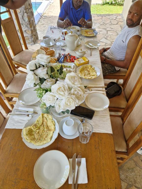 deux personnes assises à une table avec de la nourriture dessus dans l'établissement Exclusive Beach Villa with Pool by Casa, à Kribi