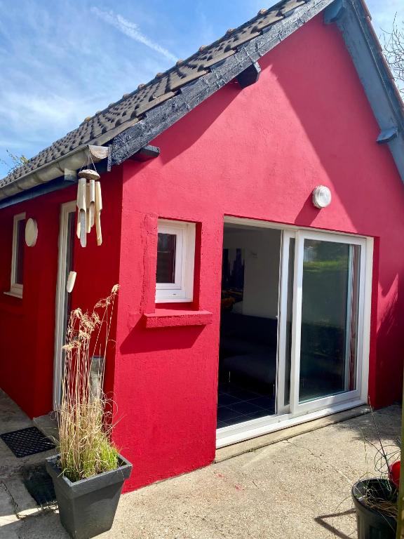 une maison rouge avec une grande fenêtre sur elle dans l'établissement La petite maison rouge, à Cucq