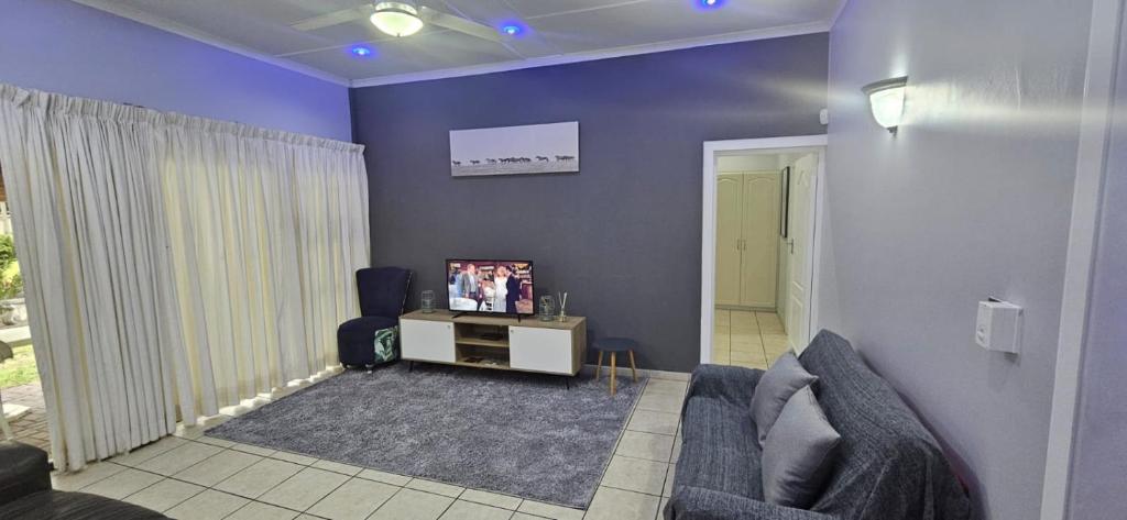 een woonkamer met een bank en een tv bij Meerensee Cottage in Richards Bay
