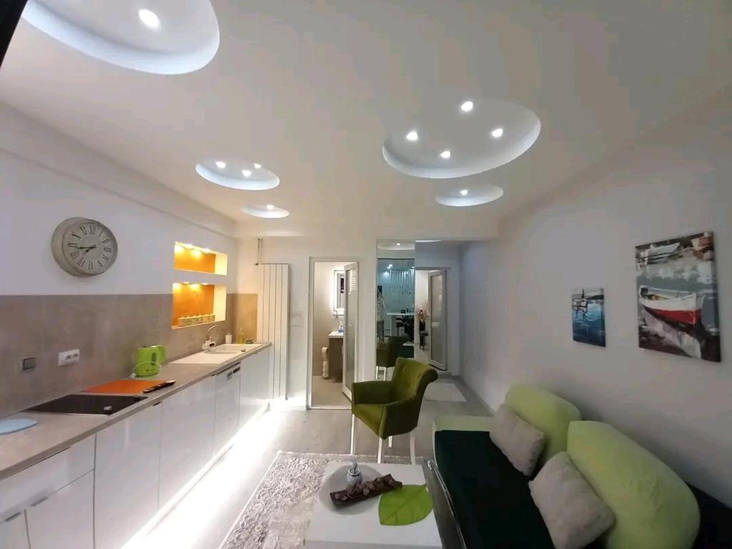 a living room with a green couch and a kitchen at Sarajevo apartman Ilidza Springs parking free in Sarajevo