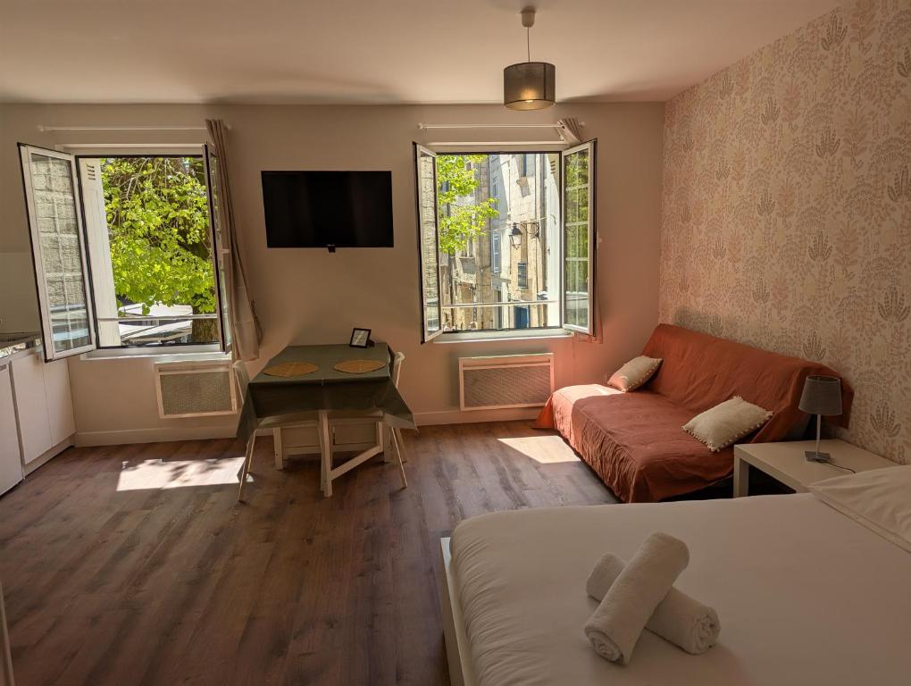 Cette chambre comprend un lit, un canapé et deux fenêtres. dans l'établissement Studios du Marché au Bois, à Périgueux