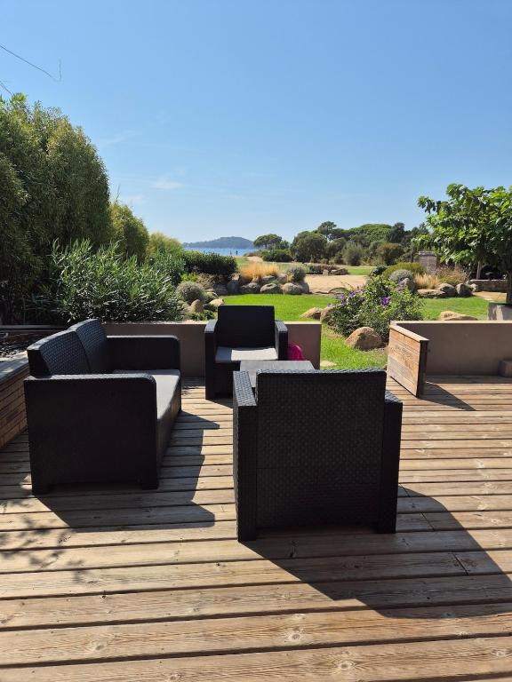 une terrasse en bois avec des canapés et des chaises. dans l'établissement Corse du Sud Villa les pieds dans l'eau !, à Zonza