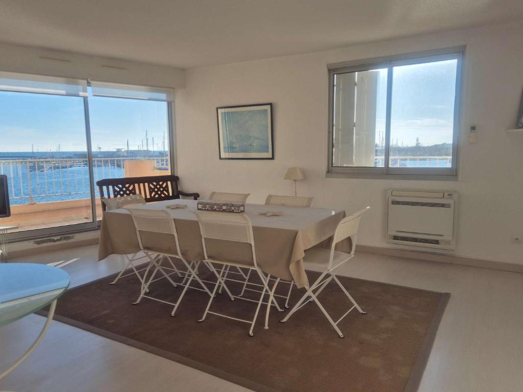 une salle à manger avec une table et des chaises et une grande fenêtre dans l'établissement Appartement 3 pièces - Vue sur port - CAP D 'AGDE CT345-029, au Cap d'Agde