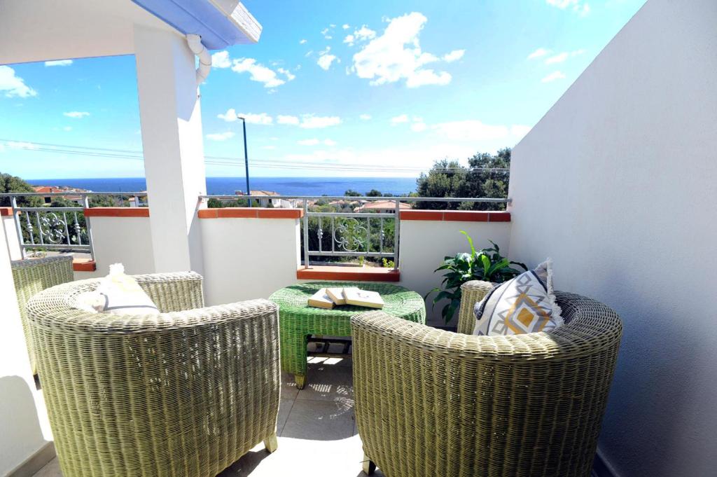 een balkon met rieten stoelen en een groene tafel bij Suite Torrigiani in Cala Gonone