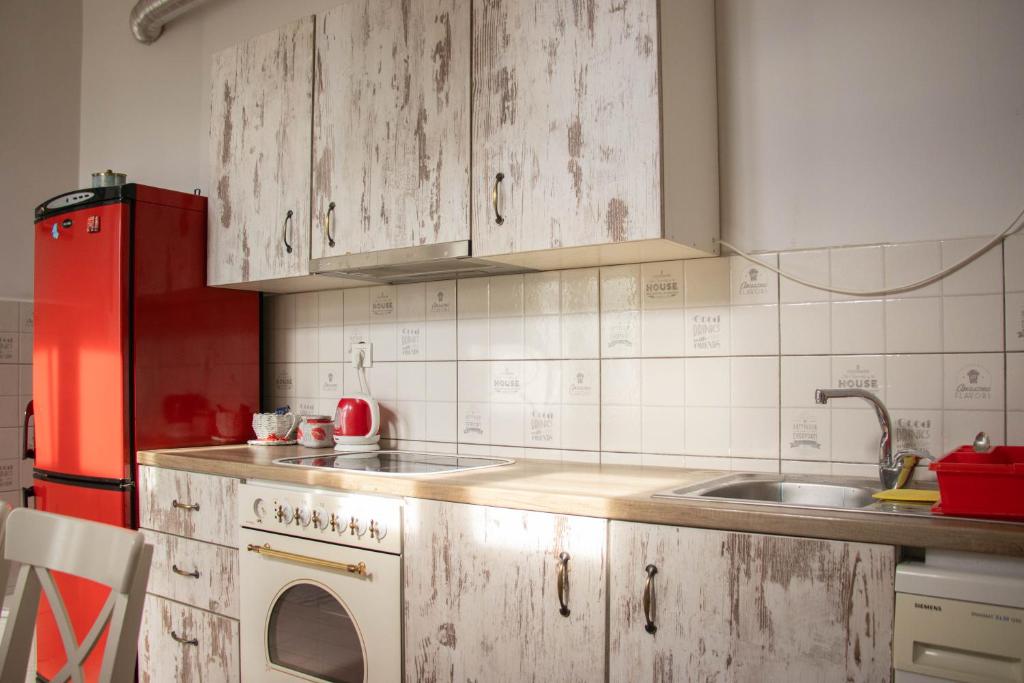 a kitchen with white cabinets and a red refrigerator at Apartment By the River in Niš