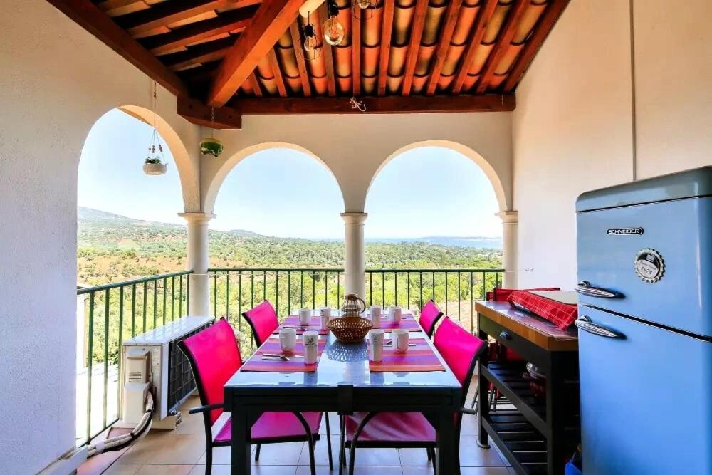 une salle à manger avec une table et des chaises roses sur un balcon dans l'établissement Les Restanques vue mer violettes 1167, à Grimaud