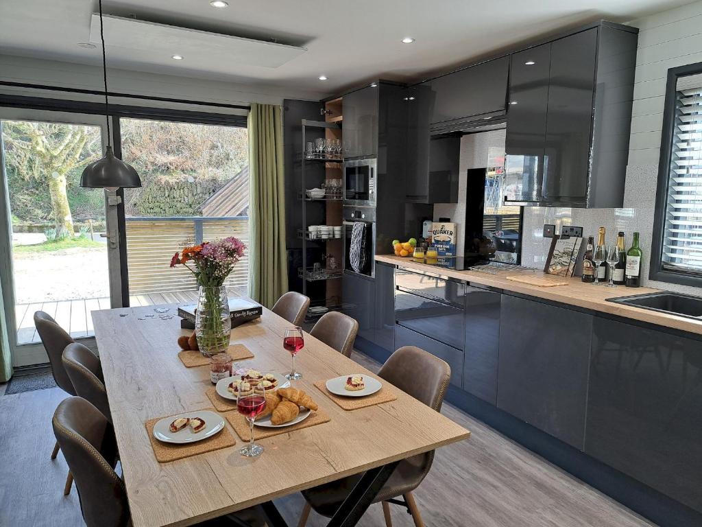 a dining room with a table and a kitchen at Cardinham Lodge 3 bedroom - max 6 occ - VP4 in Looe