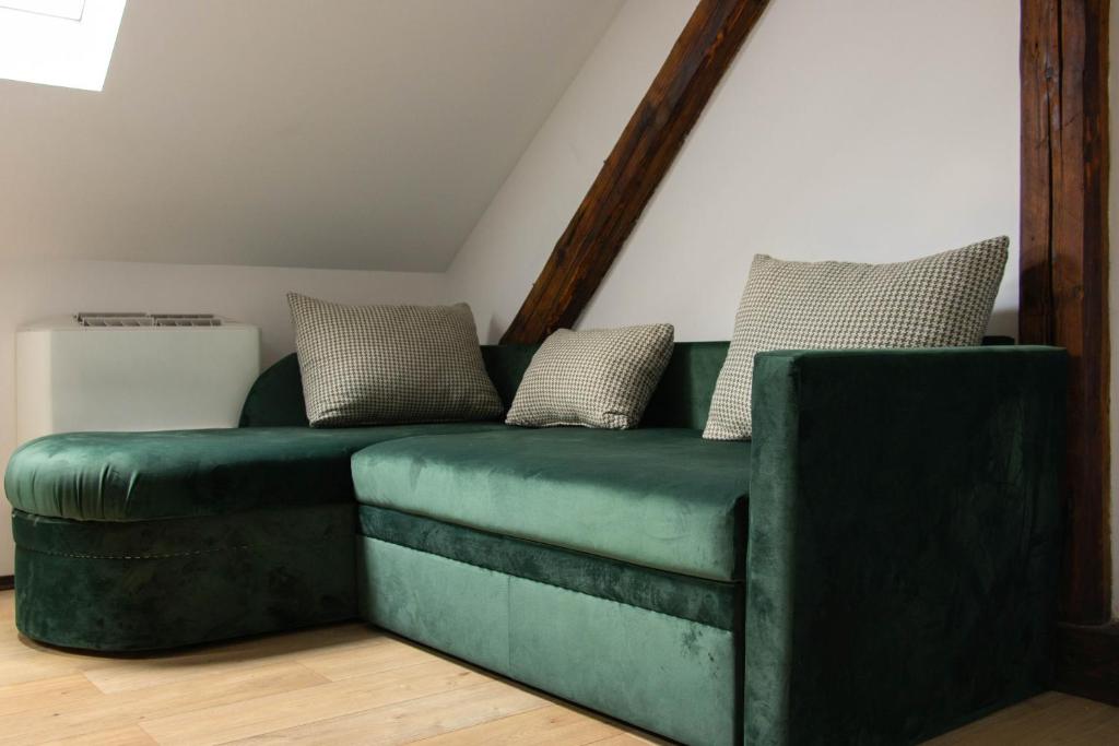 a green couch with pillows on it in a room at Apartment By the River in Niš