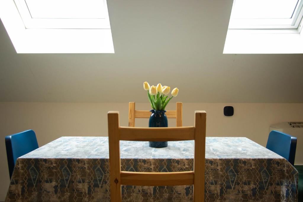 a table with a vase with yellow flowers on it at Apartment By the River in Niš