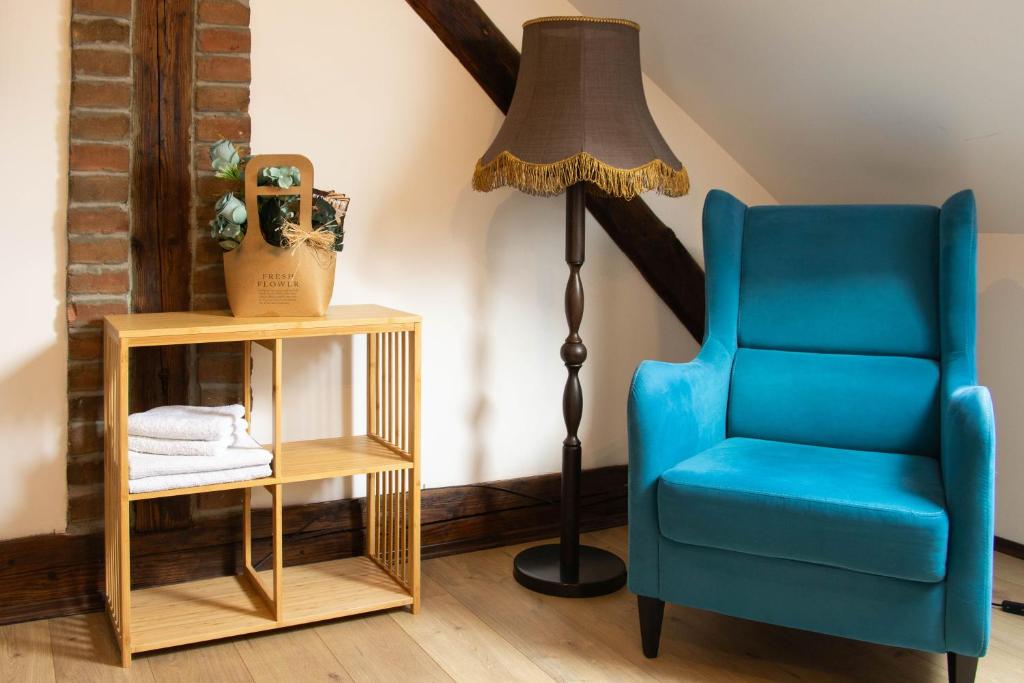 a lamp and a blue chair next to a table at Apartment By the River in Niš
