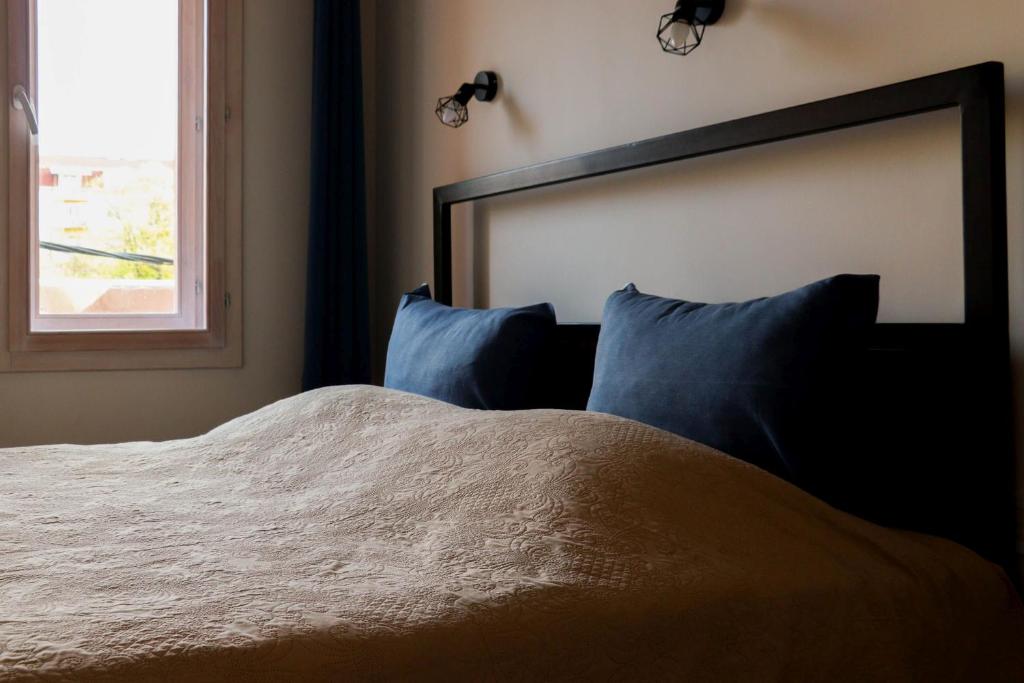 a bedroom with a bed with blue pillows and a window at Apartment By the River in Niš