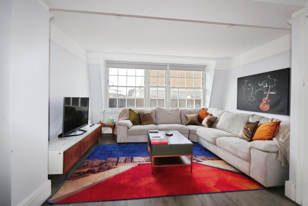 a living room with a couch and a tv at Large 3 bedrm apartment in heart of Theatre Land in London