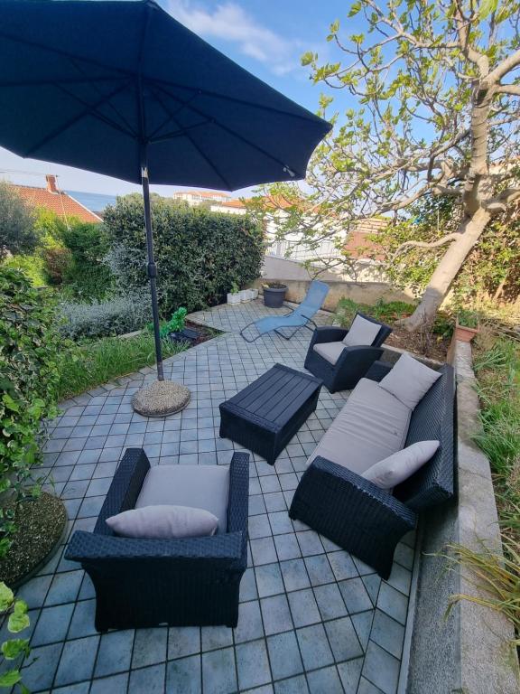 a patio with two couches and an umbrella at Apartment Lavanda in Pješčana Uvala