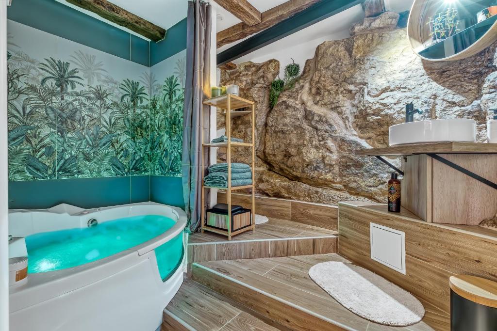 a bathroom with a tub and a rock wall at Secret room jacuzzi vieille ville Annecy in Annecy