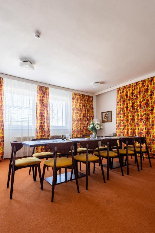 a dining room with tables and chairs and curtains at Retro Hotel JISKRA in Čeladná
