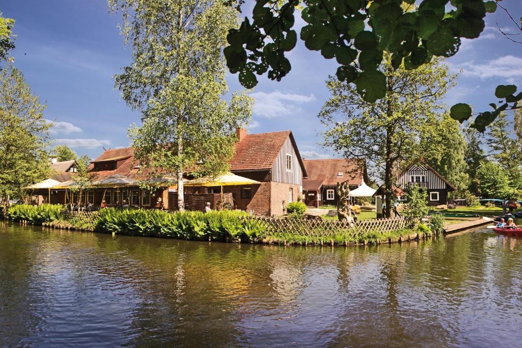 un edificio junto a un río con una casa en Pension & Biergarten Spreewaldhof Leipe, en Leipe