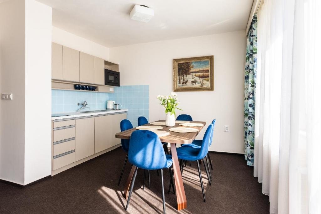 a kitchen with a wooden table and blue chairs at Retro Hotel JISKRA in Čeladná