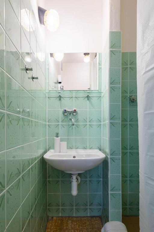 a green tiled bathroom with a sink and a mirror at Retro Hotel JISKRA in Čeladná