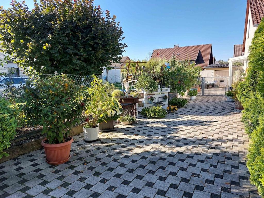 a garden with potted plants and trees on a sidewalk at Cebullas Ferienwohnung in Herzberg am Harz